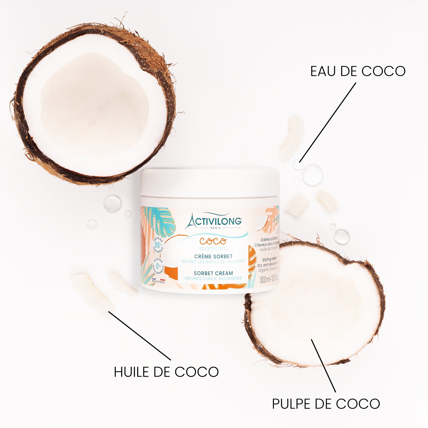 Pot de Crème sorbet Coco d'Amour entouré de ses actifs sur fond blanc : deux demi-noix de coco fraîches, morceaux de pulpe de coco, huile de coco et gouttes d'eau de coco, avec les mentions « Eau de coco », « Huile de coco » et « Pulpe de coco ».