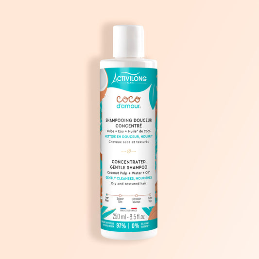 Visuel du flacon Shampooing douceur concentré Coco d'Amour de face sur fond pêche uni, packaging turquoise aux motifs de noix de coco