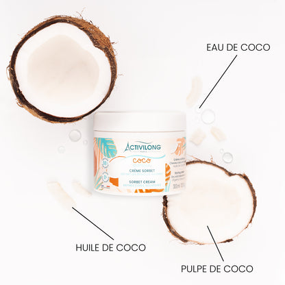 Pot de Crème sorbet Coco d'Amour entouré de ses actifs sur fond blanc : deux demi-noix de coco fraîches, morceaux de pulpe de coco, huile de coco et gouttes d'eau de coco, avec les mentions « Eau de coco », « Huile de coco » et « Pulpe de coco ».