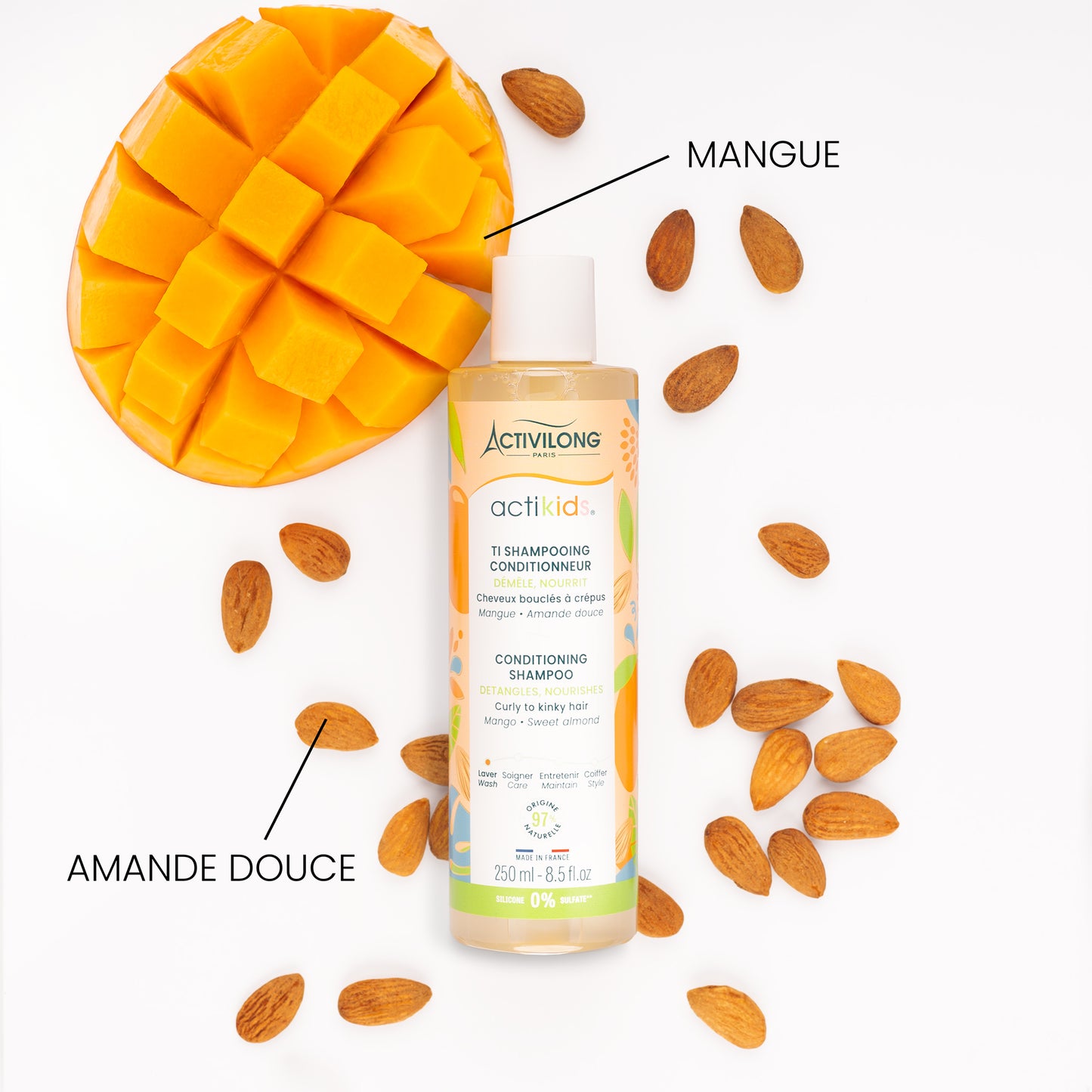 Flacon du Ti Shampooing Conditionneur Actikids entouré de ses actifs sur fond blanc : amandes douces et mangue coupée en cubes, avec les mentions « Mangue » et « Amande douce ».