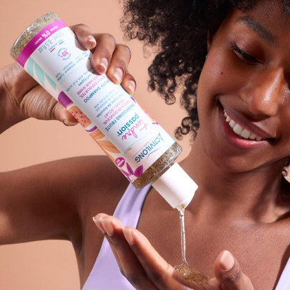 Visuel d'une femme aux cheveux bouclés versant le Shampooing fruité Tendre Passion dans le creux de sa main, le gel aux graines de maracuja coulant