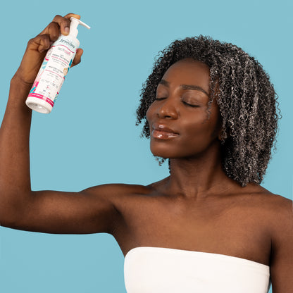 Visuel d'une femme aux cheveux crépus, yeux clos, brandissant le flacon Lait thermo-protecteur Acticurl Expert Activilong, sur fond bleu clair