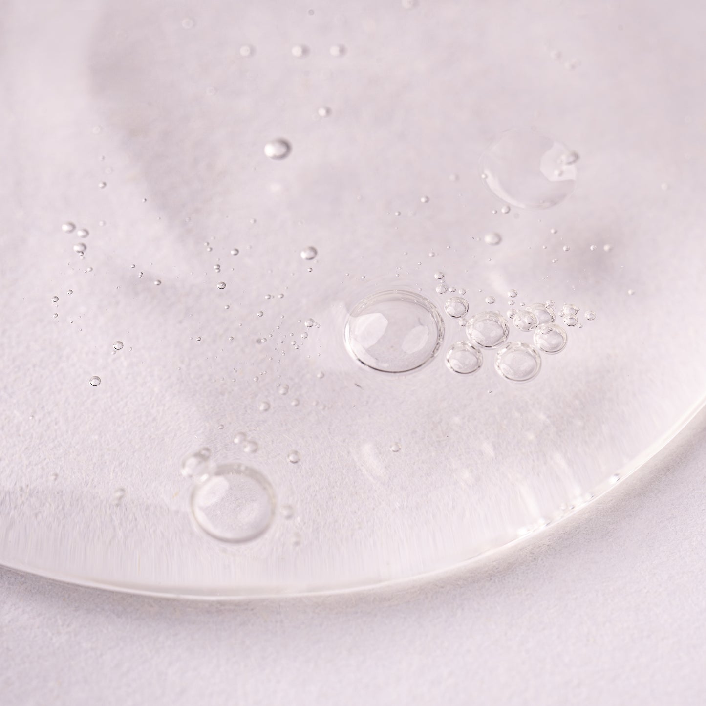 Visuel en gros plan de la texture du Gel activateur de boucles Acticurl Activilong, gel transparent parsemé de bulles d'air sur fond clair