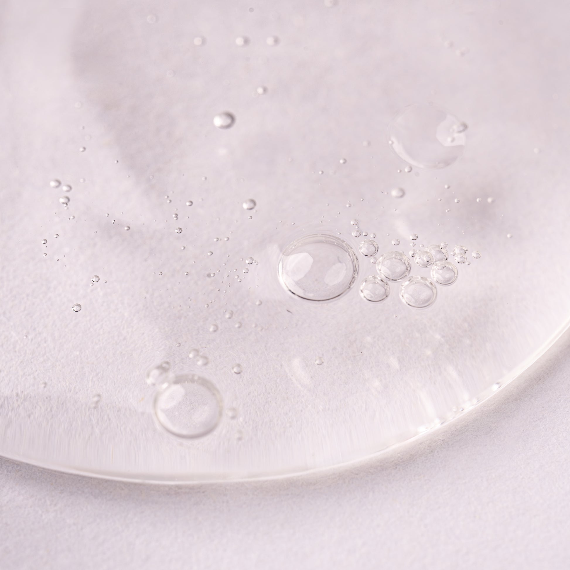 Visuel en gros plan de la texture du Gel activateur de boucles Acticurl Activilong, gel transparent parsemé de bulles d'air sur fond clair