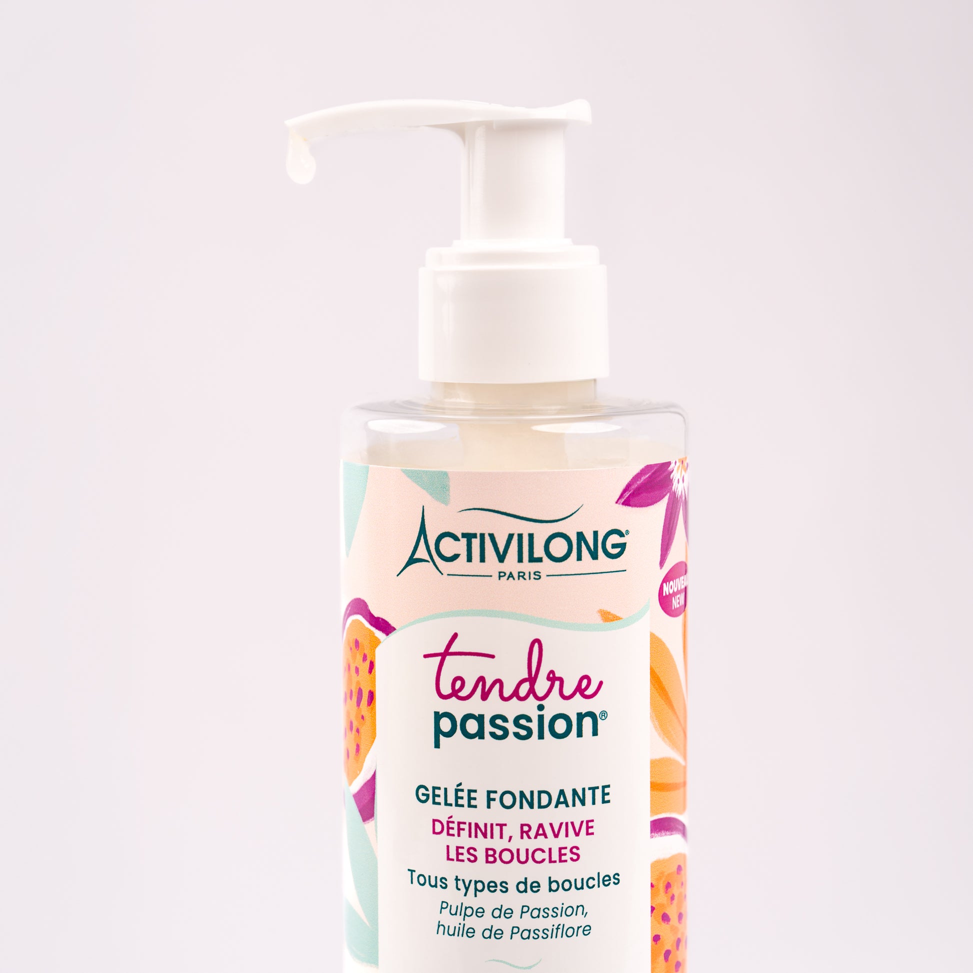 Gros plan sur le flacon-pompe de Gelée fondante Tendre Passion, une goutte de gelée translucide perlant au bout de la pompe pour révéler sa texture fluide et limpide, sur fond rose poudré clair.