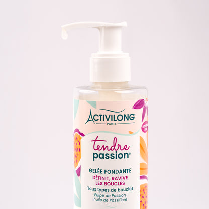 Gros plan sur le flacon-pompe de Gelée fondante Tendre Passion, une goutte de gelée translucide perlant au bout de la pompe pour révéler sa texture fluide et limpide, sur fond rose poudré clair.