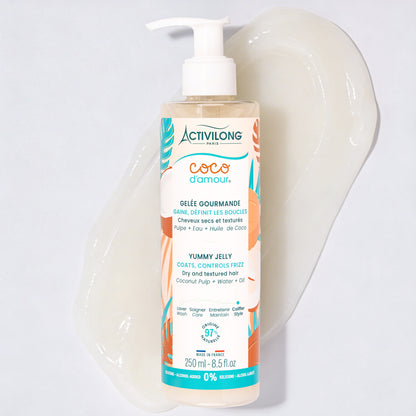 Flacon-pompe de Gelée gourmande Coco d'Amour posé sur une large trace de produit étalée, révélant sa texture de gelée translucide et brillante, sur fond gris clair.