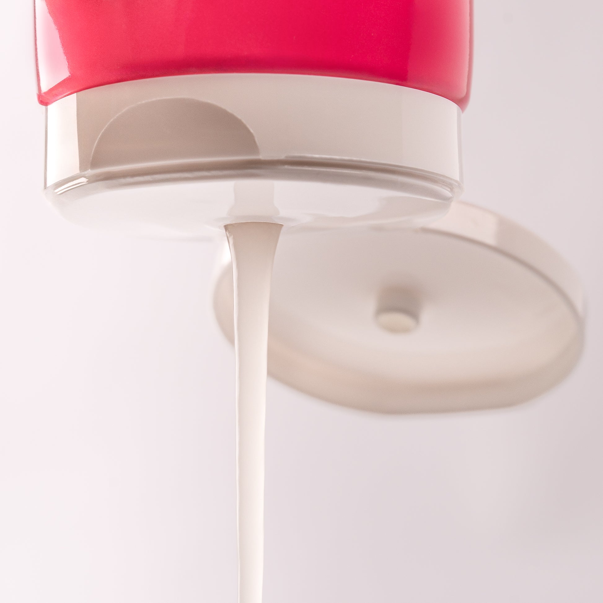 Visuel de la texture gélifiée de la Gelée Scrunching Acticurl Expert s'écoulant du bouchon sur fond clair