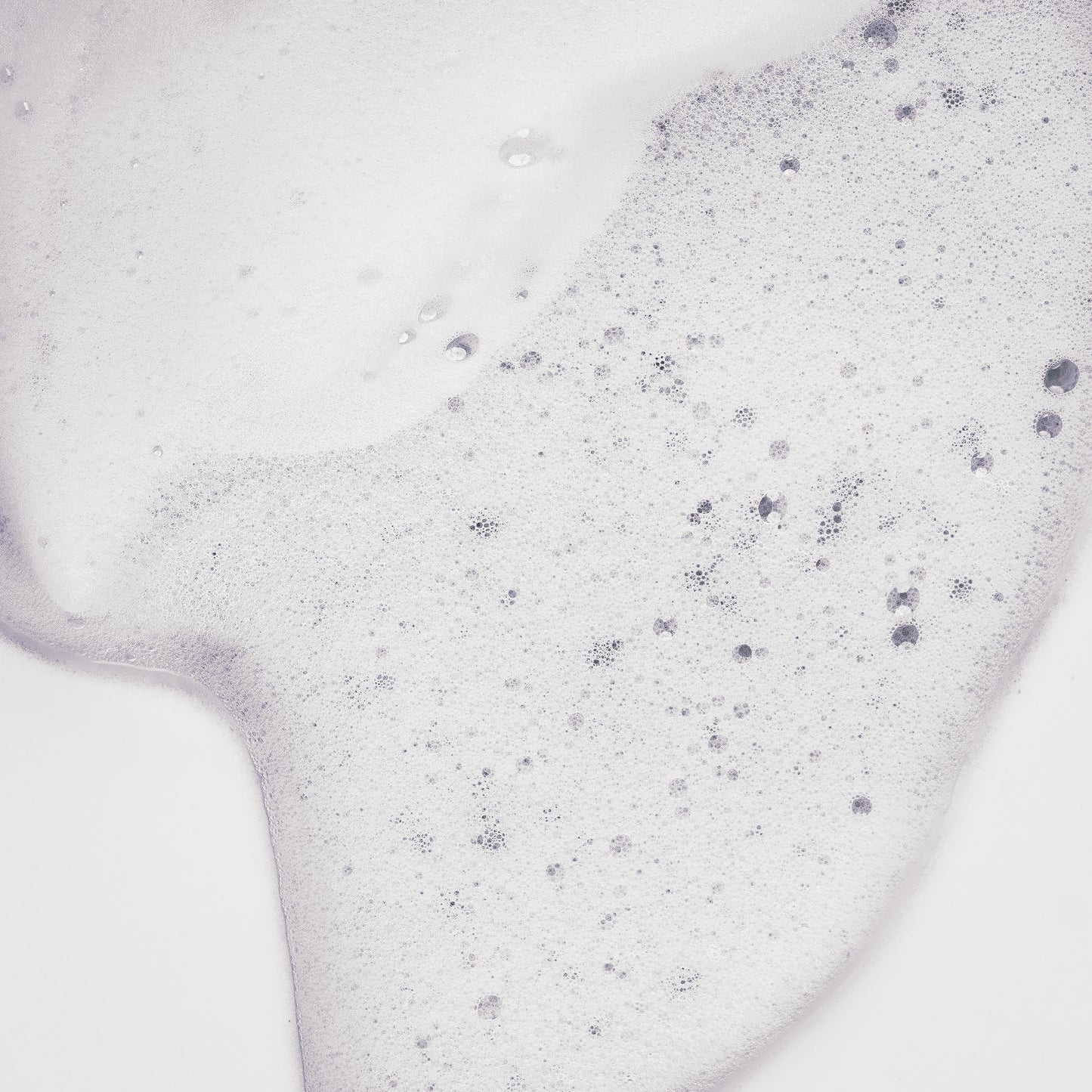 Texture de la Mousse de maracuja Tendre Passion étalée en gros plan, mousse blanche aérée et mousseuse aux fines bulles, sur fond gris clair.