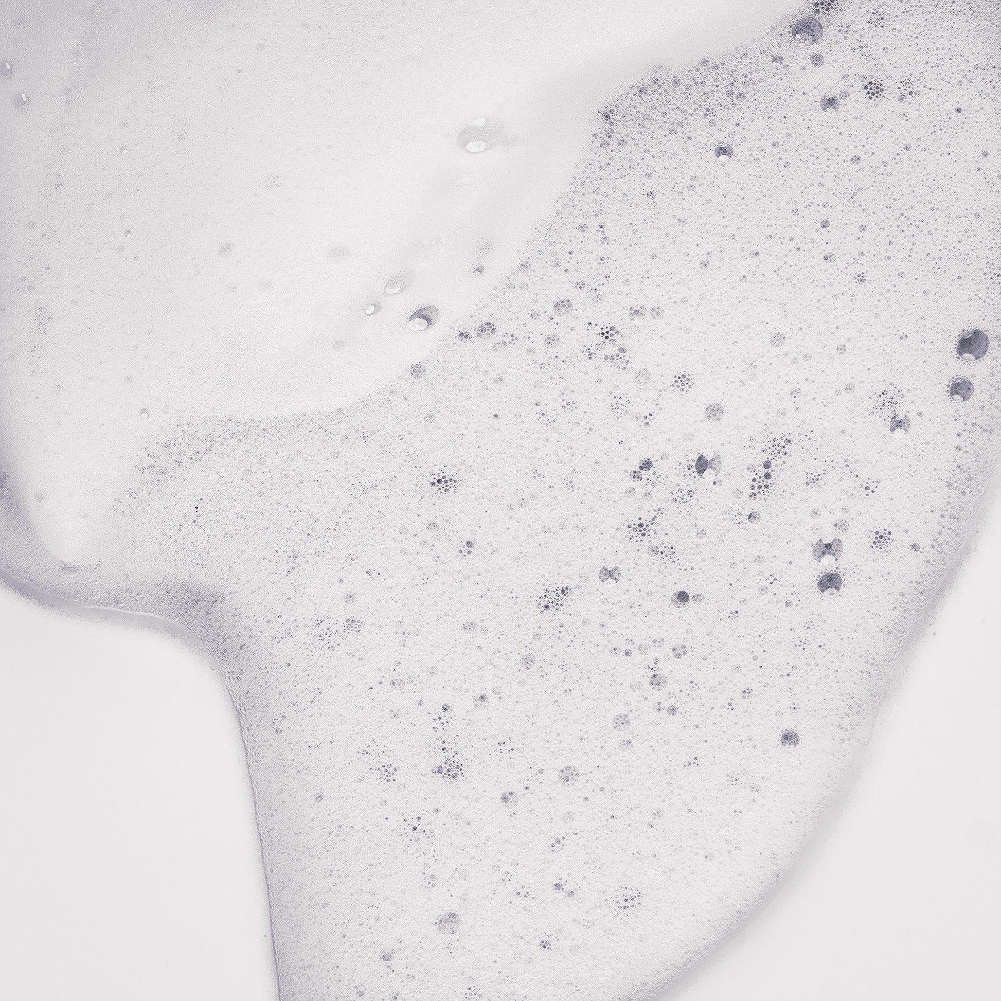 Texture de la Mousse de maracuja Tendre Passion étalée en gros plan, mousse blanche aérée et mousseuse aux fines bulles, sur fond gris clair.