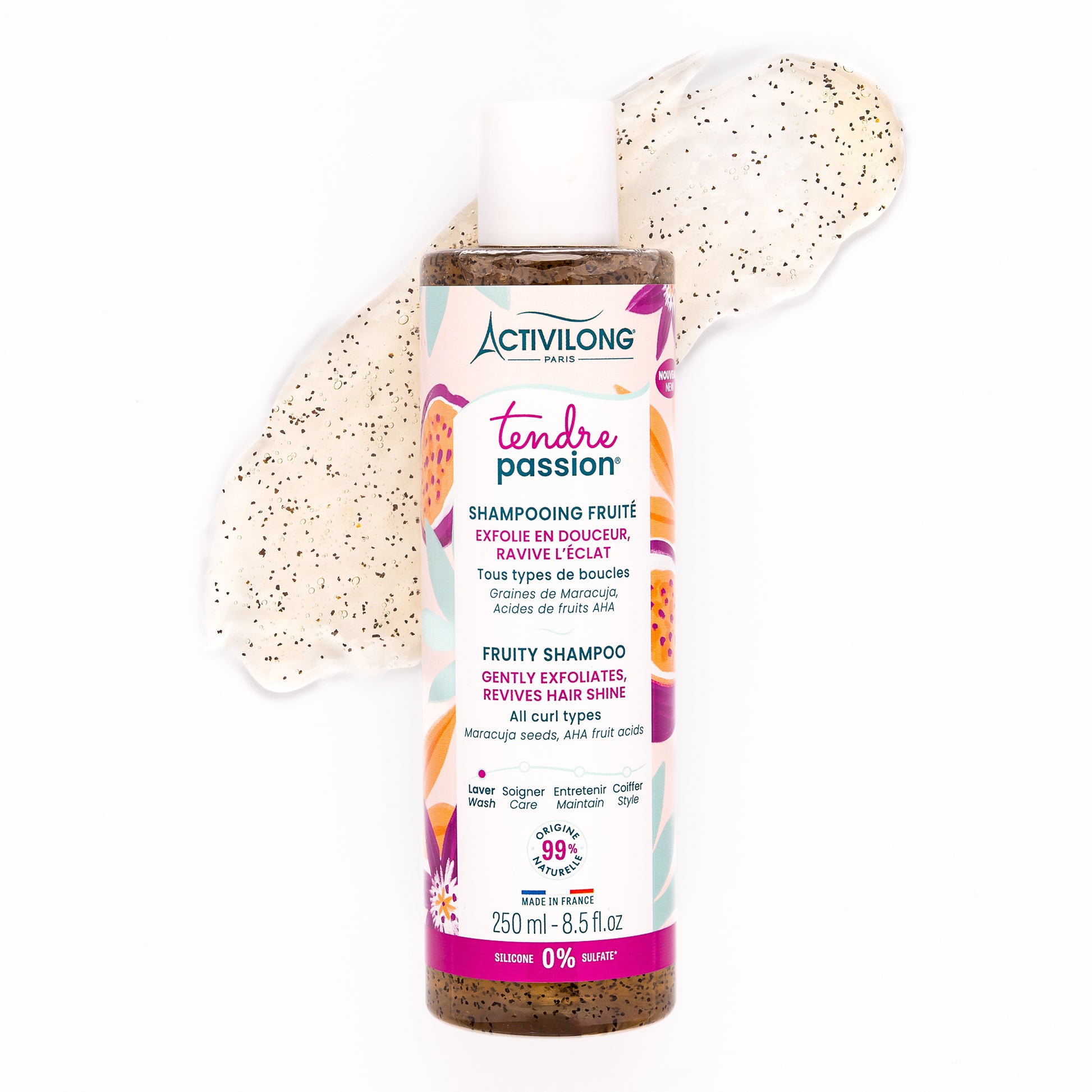 Visuel du flacon Shampooing fruité Tendre Passion couché sur fond blanc, entouré du gel exfoliant étalé aux graines de maracuja