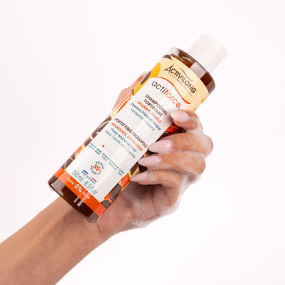 Visuel d'un Flacon du Shampooing Fortifiant Actiforce tenu dans une main couverte de mousse sur fond clair