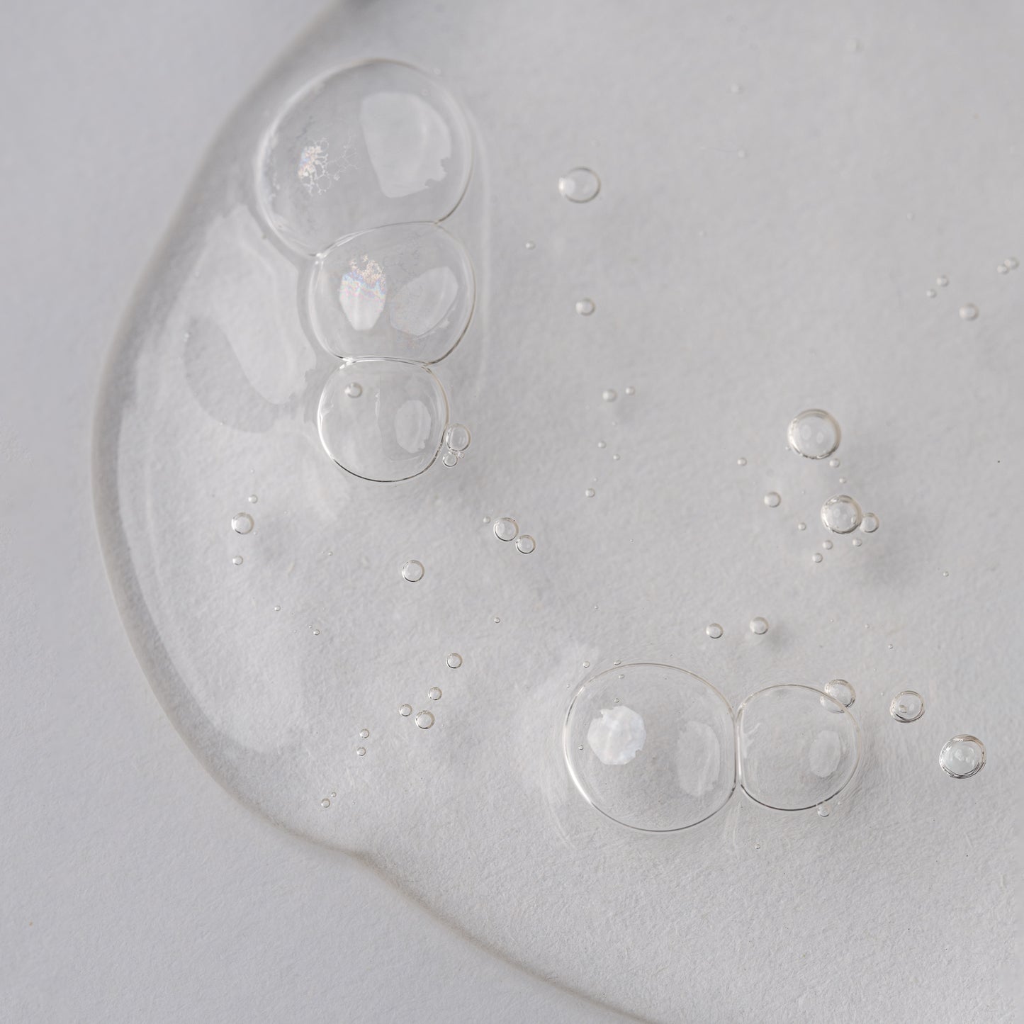 Visuel de la texture gélifiée transparente du Shampooing Purifiant Actidetox parsemée de bulles sur fond clair