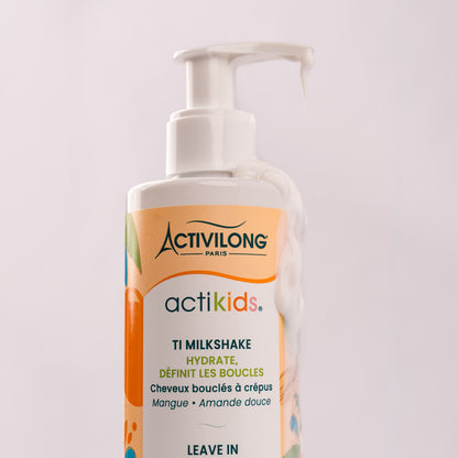 Gros plan sur le flacon-pompe du Ti Milkshake / Leave-in Actikids, le soin nappant la pompe et s'écoulant le long du flacon pour révéler sa texture onctueuse, sur fond gris clair.