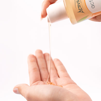 Ti Shampooing Conditionneur Actikids versé dans le creux d'une main, révélant sa texture fluide et translucide ambrée, sur fond blanc.