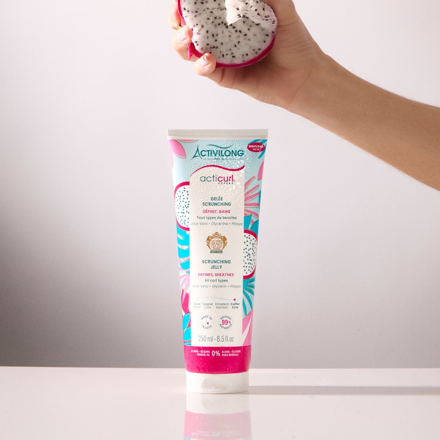 Gelée Scrunching Acticurl Expert avec un fruit de pitaya en arrière-plan tenue par une main